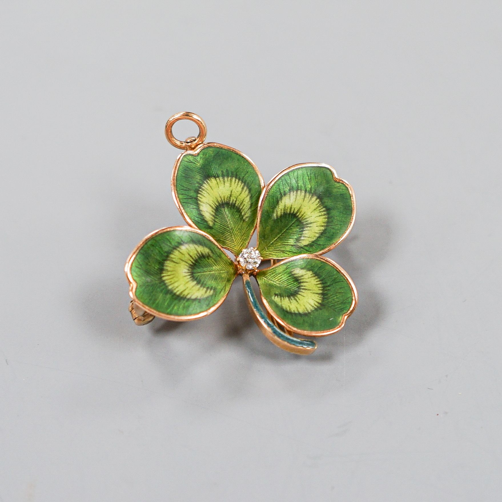 A yellow metal, two colour enamel and single stone diamond set clover pendant brooch, width 27mm, gross weight 6.6 grams.